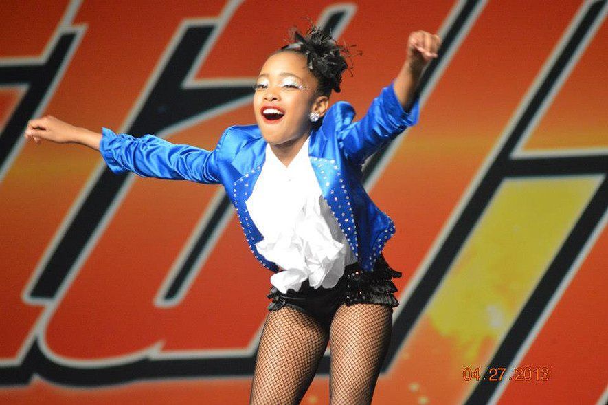 Child dancer performing with enthusiasm on stage.