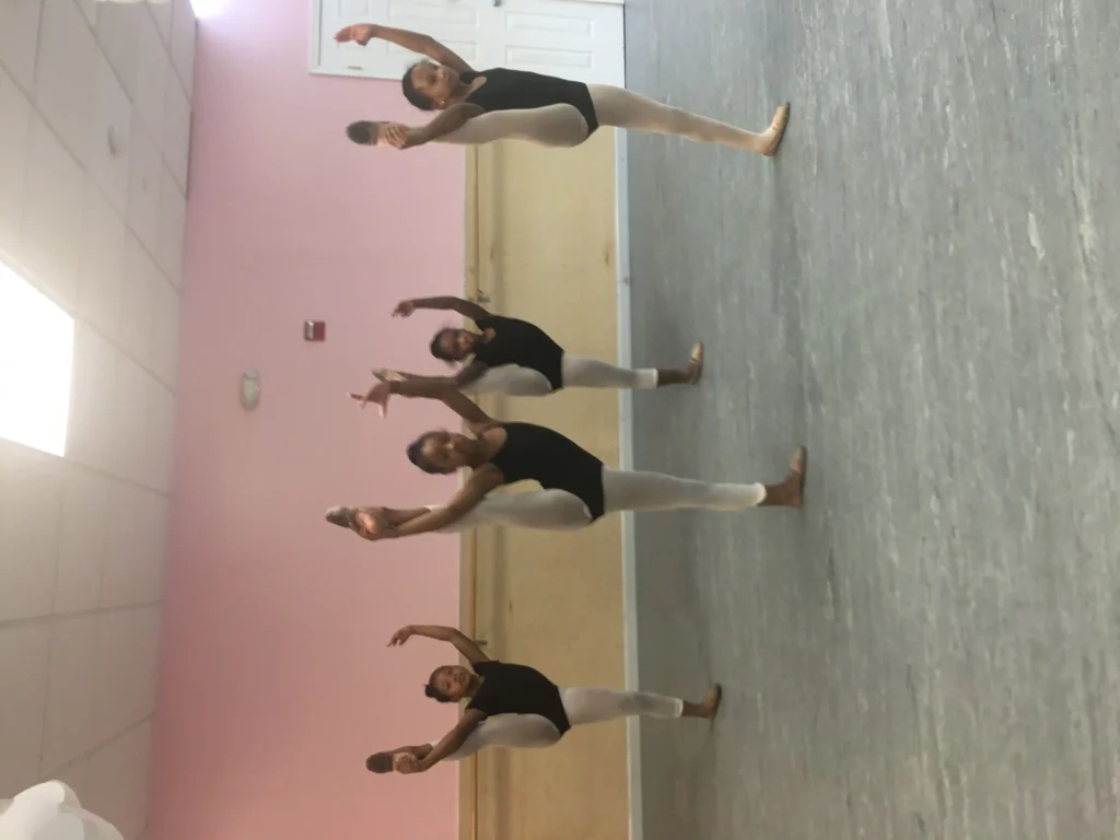 Four ballet dancers practicing in pink studio