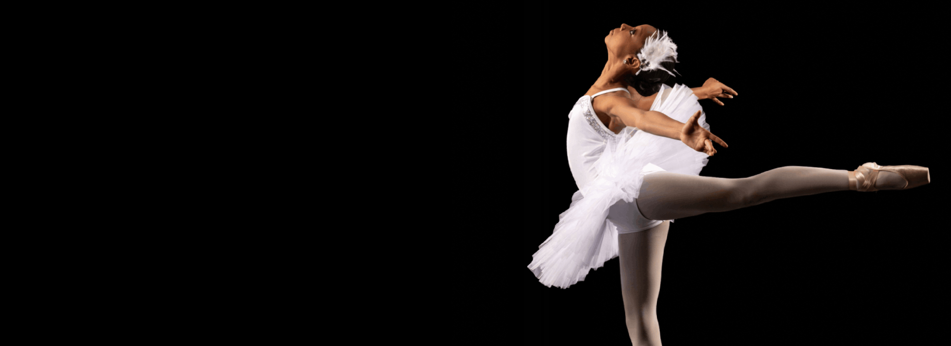 Ballet dancer in graceful pose against black background.